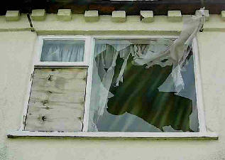 Derelict hopuse, broken window and curtains flapping.
