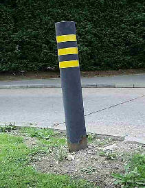Street bollard with three yellow stripes on it