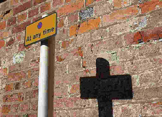 A No Parking road sign with its shadow in shape of a cross