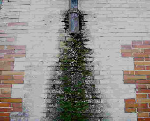 A broken downpipe with water down wall