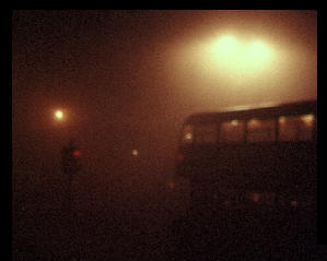 A bus in thick fog at red traffic lights