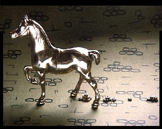 A brass model horse with brass nuts trailing behind as its droppings.